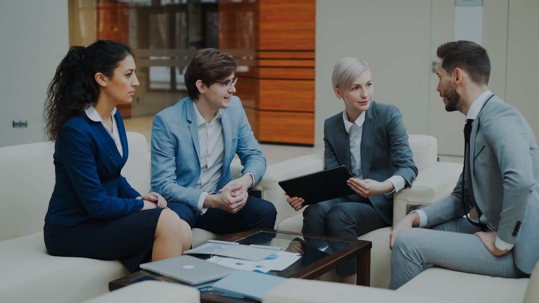 The Art of Drawing Readers In: Your attractive post title goes here Businesswoman with digital tablet talking with male and female business colleagues sitting on couch in modern office indoors