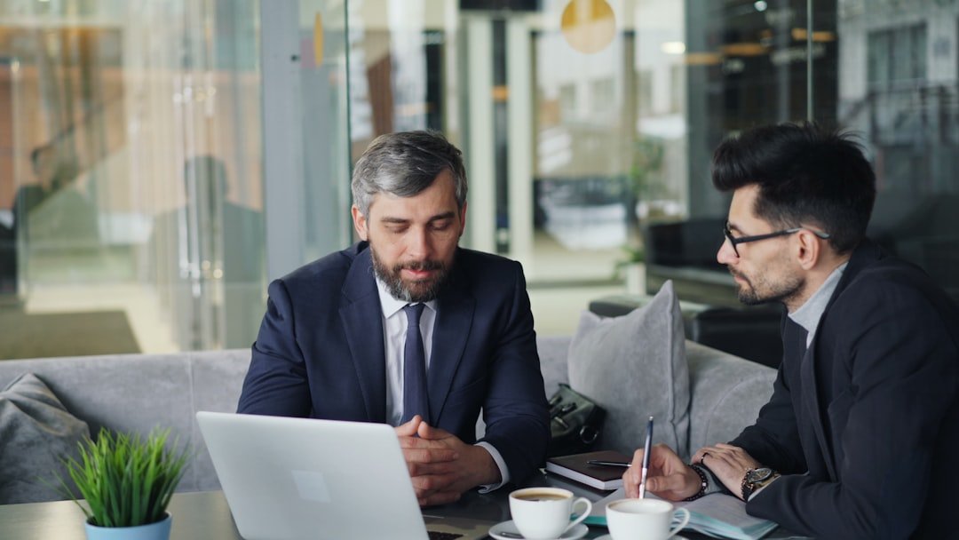 two-men-sitting-at-a-table-working-on-a-laptop-7k-37pbn0fs